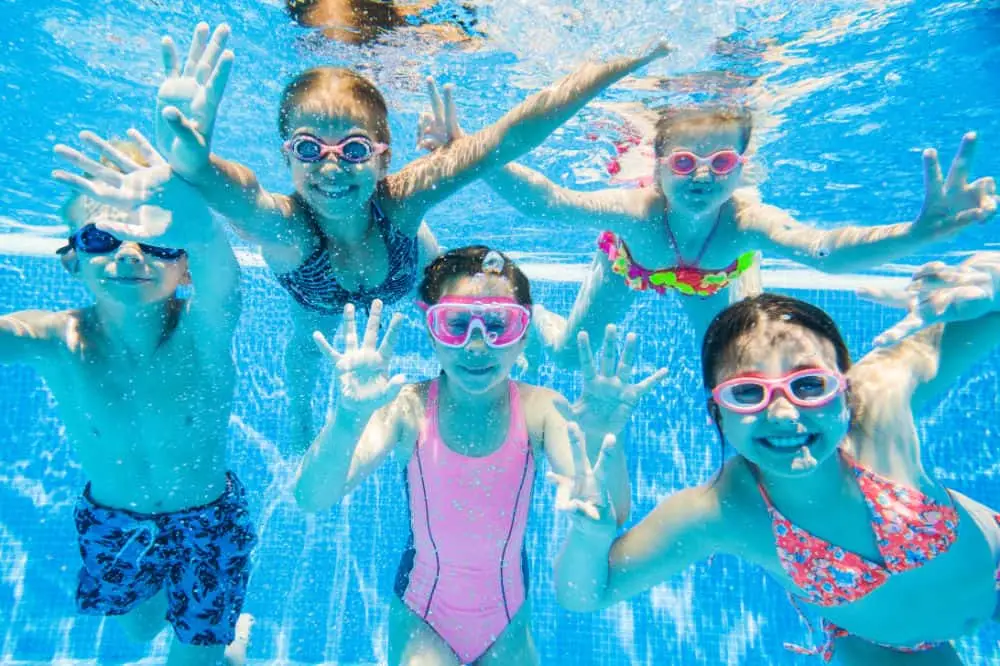 Two children swimming underwater in a clean, clear pool maintained by Simple Pool Care